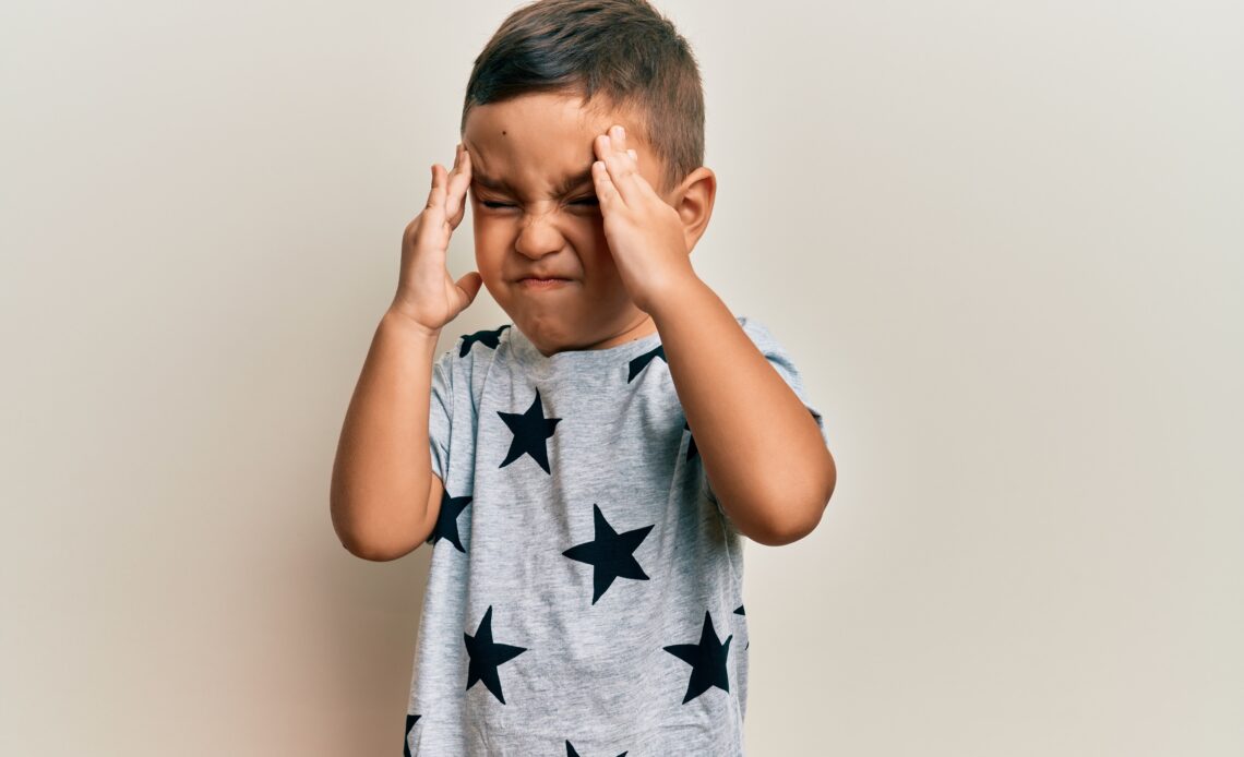 adorable latin toddler wearing casual clothes with hand head headache because stress suffering migraine