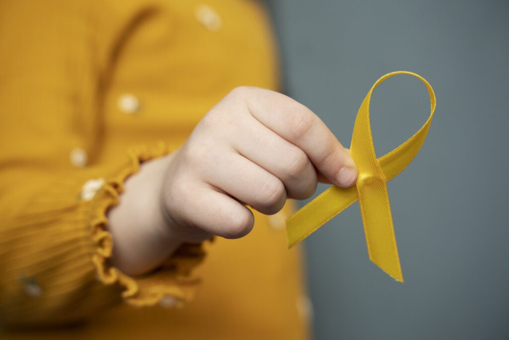 Setembro Dourado: oncopediatra alerta para diagnóstico precoce 2 child holding yellow ribbon 1024x683 1